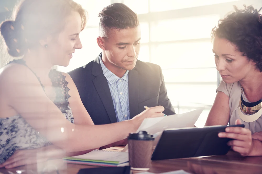 Image of three succesful business people using a tablet during at meeting