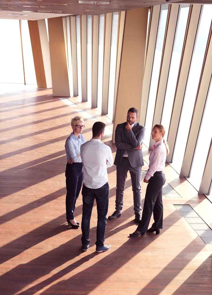 business people group standing together as team by window in modern bright office interior